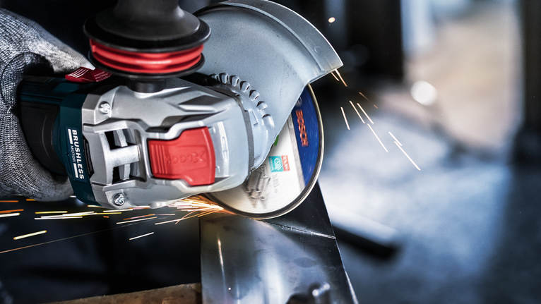 PRO Stainless Steel and Metal Bonded Cutting Disc, 125 x 1 x 22.23 mm, X-Lock, Straight A person wearing safety equipment grinds metal, creating bright sparks.
