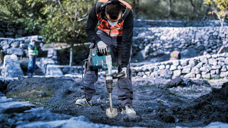 PRO SDS max Excavation Chisel, 110 x 400 mm A person wearing safety equipment uses a rotary hammer to break ground outdoors.