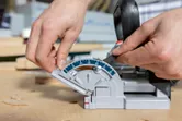 Person adjusting the angle on a biscuit joiner set on a wooden work surface.