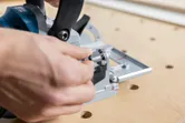 Person adjusting a biscuit joiner on a wooden workbench.