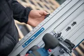 Person adjusts a track guide rail with measurement markings on a construction site.