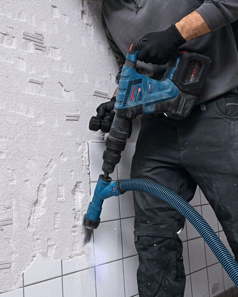 GSH 18V-5 A person wearing safety equipment uses a cordless demolition hammer to break wall tiles.