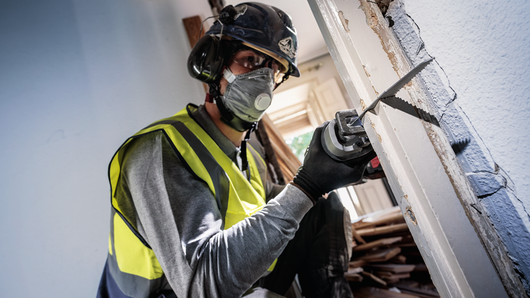 PRO Multi Material Demolition S1110VF Blade, 1.6 x 22 x 225 mm, 5 pcs Person wearing safety equipment cuts a doorframe with a reciprocating saw.