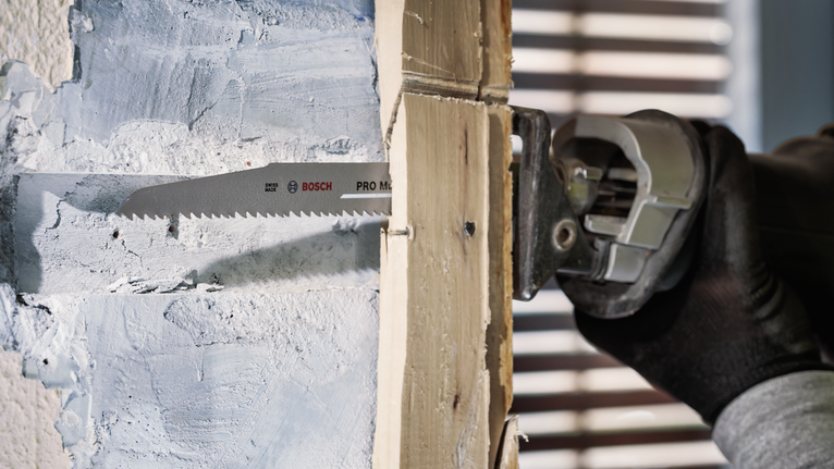 PRO Multi Material Demolition S1110VF Blade, 1.6 x 22 x 225 mm, 5 pcs Person wearing safety equipment cuts through plaster and wood with a reciprocating saw.