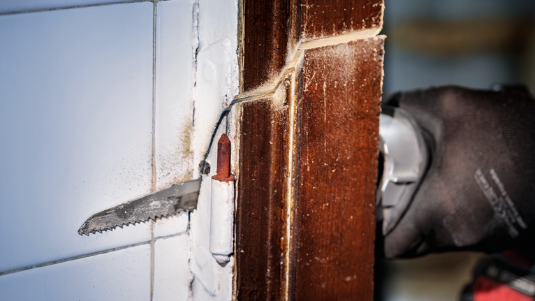 PRO Multi Material Demolition S1110VF Blade, 1.6 x 22 x 225 mm, 5 pcs Person wearing safety equipment cuts a wooden door frame with a reciprocating saw.
