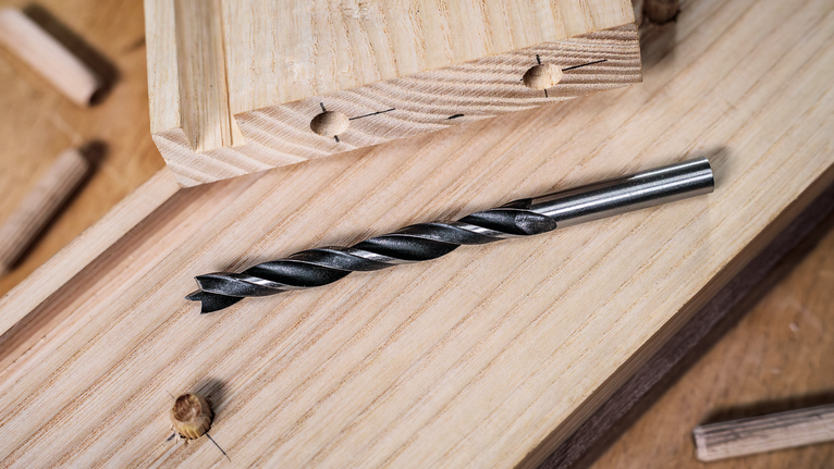 PRO Wood Brad Point Drill Bit Set, 8 pcs Drill bit placed on wooden planks with dowels nearby.