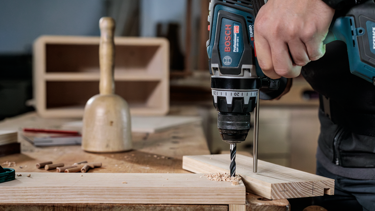 PRO Wood Brad Point Drill Bit Set, 8 pcs Person using a power drill to create a hole in a wooden board.