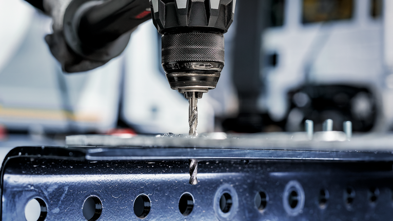 PRO Metal HSS-G Twist Drill Bit, 1/4 x 63 x 101 mm Power drill boring a hole through a metal beam in an industrial setting.