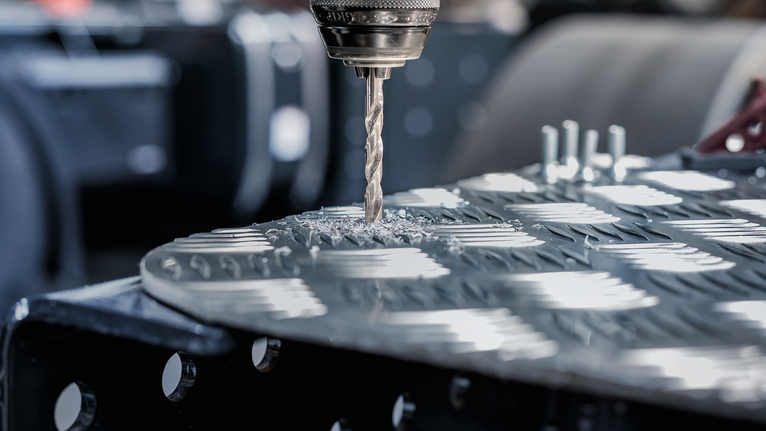 PRO Metal HSS-G Twist Drill Bit, 1/4 x 63 x 101 mm Drill making a hole in a textured metal sheet.