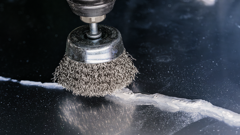PRO Metal clean Cup Brush, Straight Shank, 50 x 0.2 mm Wire cup brush smoothing a crack on a dark metal surface.