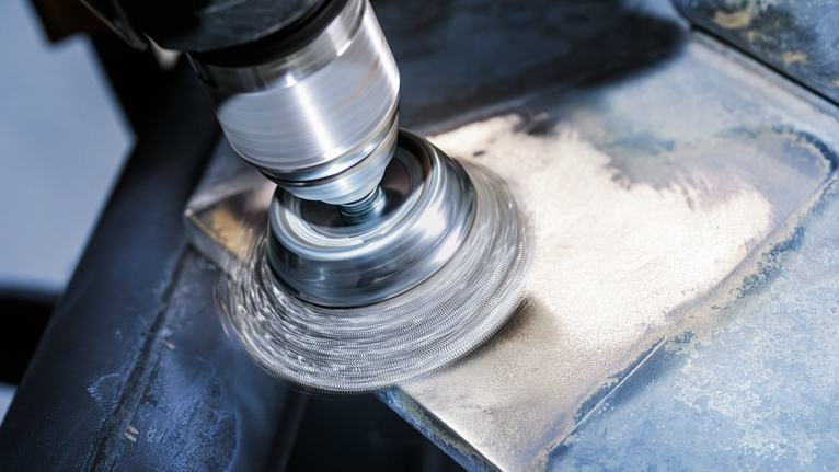 PRO Metal clean Cup Brush, Straight Shank, 50 x 0.2 mm Angle grinder with wire brush attachment cleaning the surface of a metal sheet.