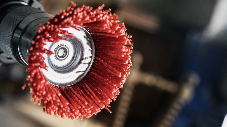 PRO Multi Material clean Cup Brush, 75 x 1 mm, Straight Shank Red abrasive wheel brush attached to a power tool for metal surface preparation.