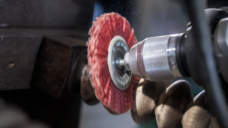 PRO Multi Material clean Cup Brush, 75 x 1 mm, Straight Shank Person wearing safety equipment uses a power tool with a red abrasive disc on metal.