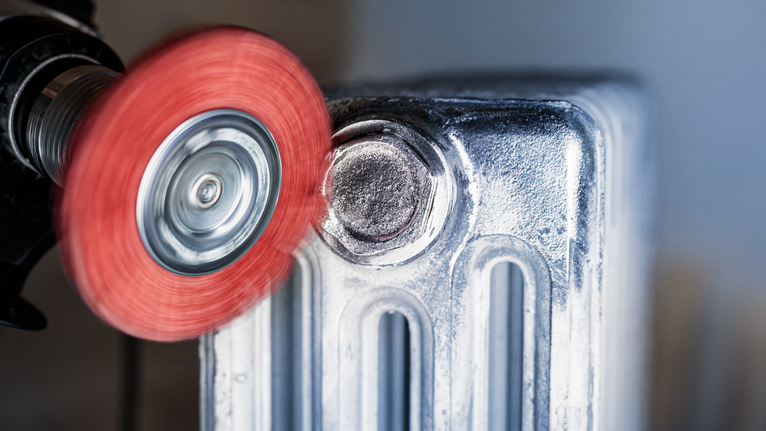 PRO Multi Material clean Cup Brush, 75 x 1 mm, Straight Shank Red abrasive wheel grinding a metal radiator surface.