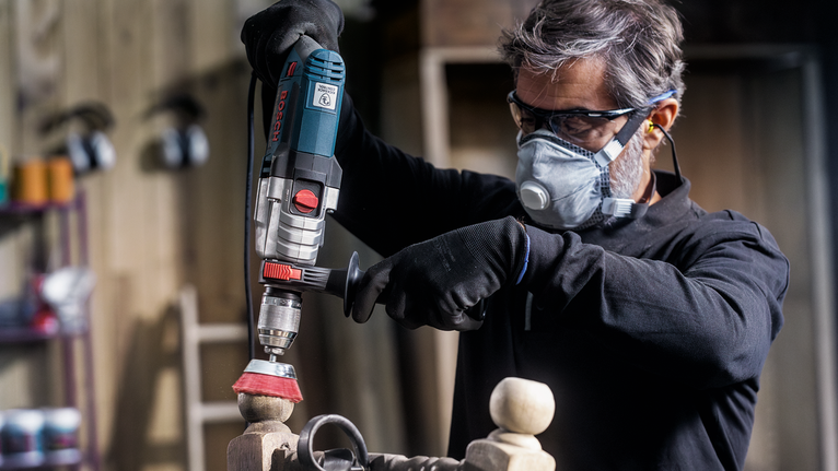 PRO Multi Material clean Cup Brush, 75 x 1 mm, Straight Shank Person wearing safety equipment polishes wooden furniture using a power tool.