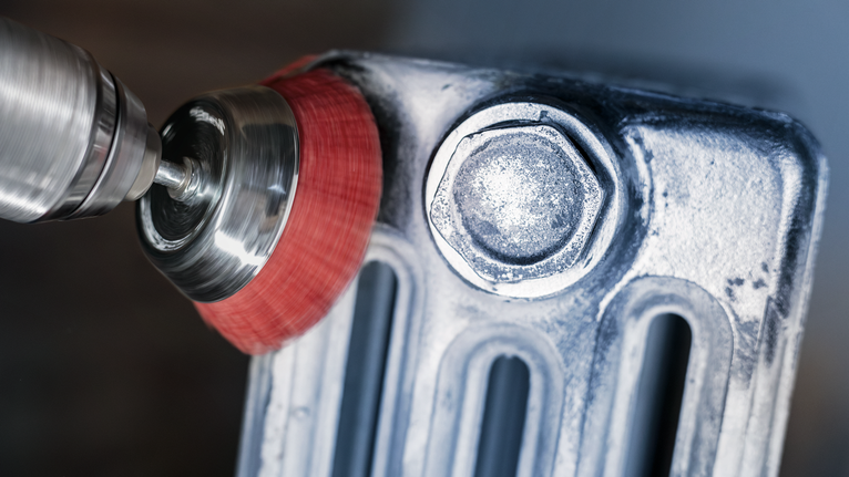 PRO Multi Material clean Cup Brush, 75 x 1 mm, Straight Shank Wire brush drill attachment cleaning a metal surface near a large bolt.