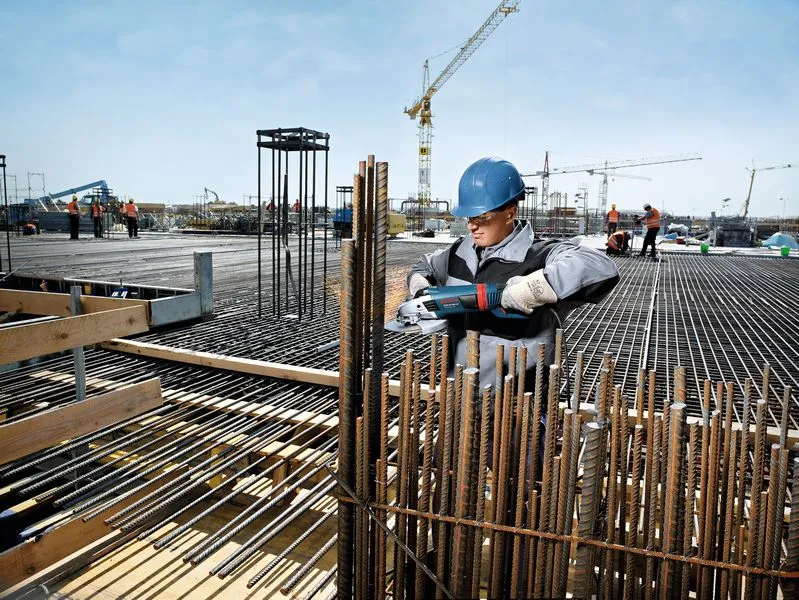 Worker cutting rebar, construction site.