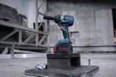 Cordless impact wrench standing on a metal block at a construction site.