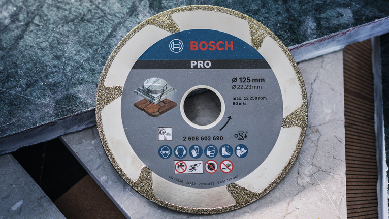PRO Marble Diamond Disc, 115 x 22.23 mm Diamond cutting disc placed on stacked tile slabs.
