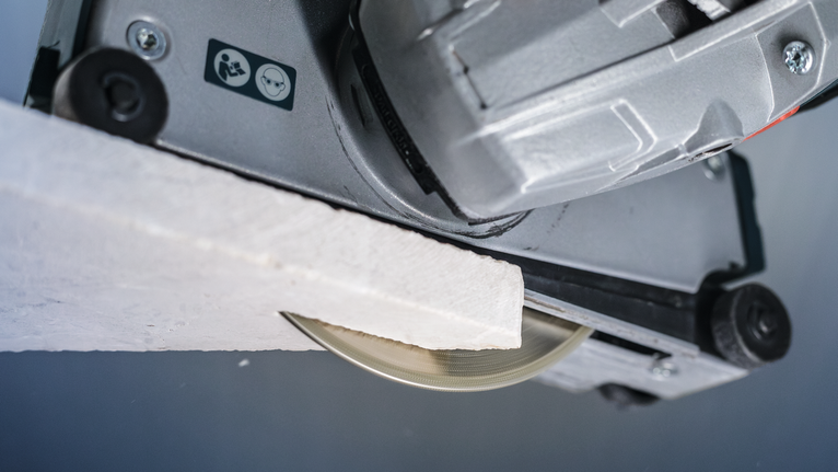 PRO Marble Diamond Disc, 115 x 22.23 mm Circular saw blade cutting through a piece of white construction material.