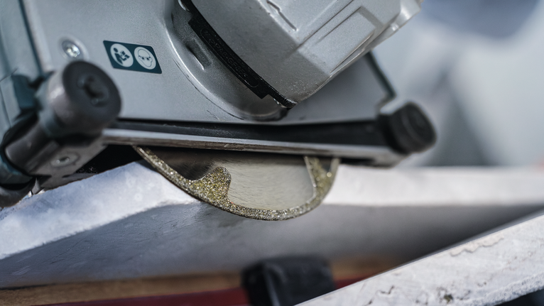PRO Marble Diamond Disc, 115 x 22.23 mm Diamond saw blade cuts through a piece of stone.