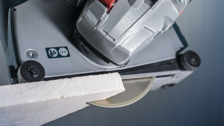 PRO Marble Diamond Disc, 115 x 22.23 mm Tile saw cutting a white tile, safety symbols visible on the tool.