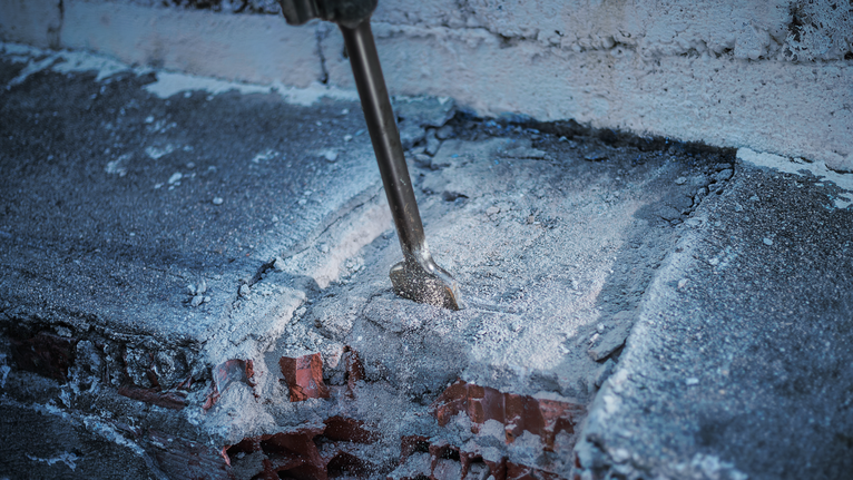 PRO HEX 30-4C Spade Chisel, 75 x 450 mm Demolition hammer breaking through a concrete and brick wall.