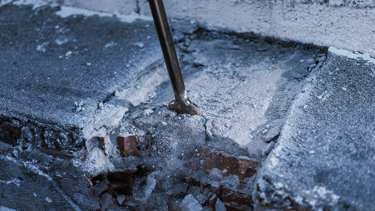 PRO HEX 30-4C Spade Chisel, 75 x 450 mm Chisel breaks through a concrete surface with dust and debris scattered.