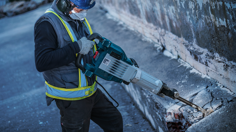 PRO HEX 30-4C Spade Chisel, 75 x 450 mm A person wearing safety equipment uses a demolition hammer to break concrete.