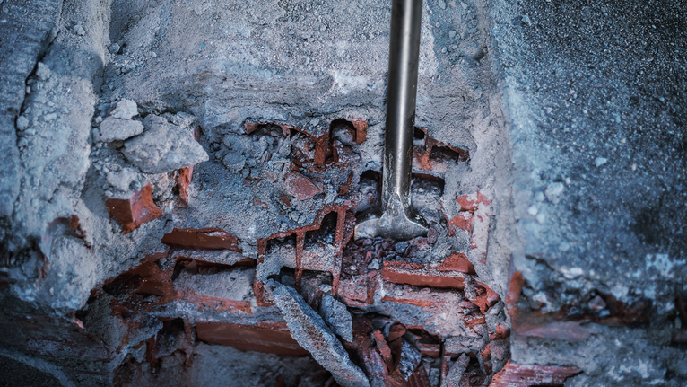 PRO HEX 30-4C Spade Chisel, 75 x 450 mm Rotary hammer chisel breaking through a damaged concrete and brick wall.