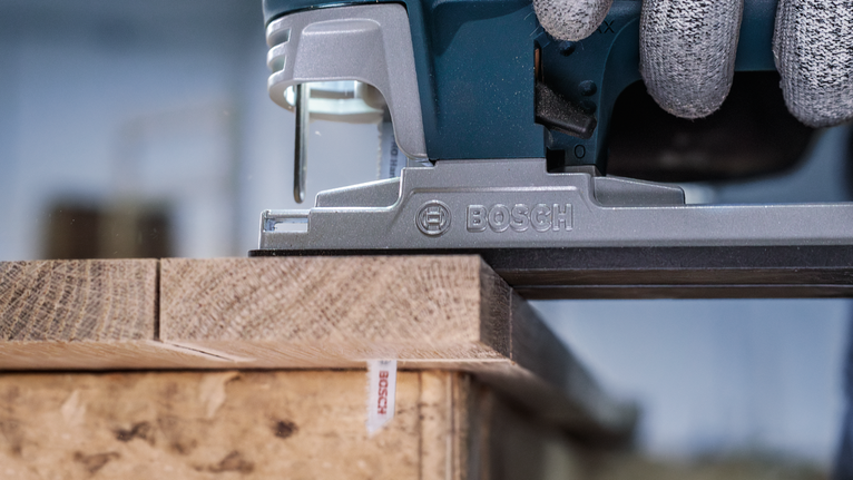 PRO Hardwood clean T101AIF Jigsaw Blade, 100 mm, 5 pcs Person wearing safety equipment uses a jigsaw to cut a wooden board.