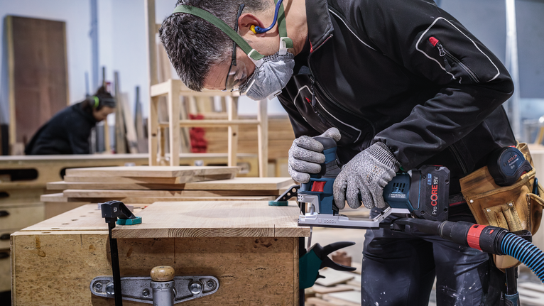 PRO Hardwood clean T101AIF Jigsaw Blade, 100 mm, 5 pcs A person wearing safety equipment uses a power tool to cut wood on a workbench.