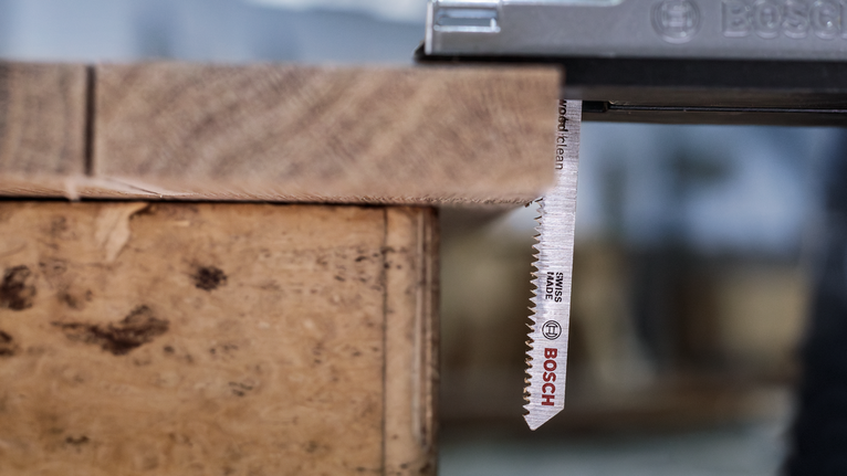 PRO Hardwood clean T101AIF Jigsaw Blade, 100 mm, 5 pcs Jigsaw blade cutting through a wooden plank in a workshop.