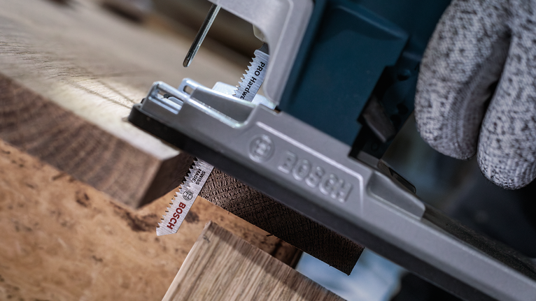 PRO Hardwood clean T101AIF Jigsaw Blade, 100 mm, 5 pcs Person wearing safety equipment uses a jigsaw to cut a wooden board.