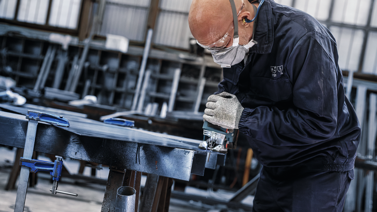 PRO Metal thick and thin T123XF Jigsaw Blade, 100 mm, 5 pcs Person wearing safety equipment uses a power saw to cut metal in a workshop.