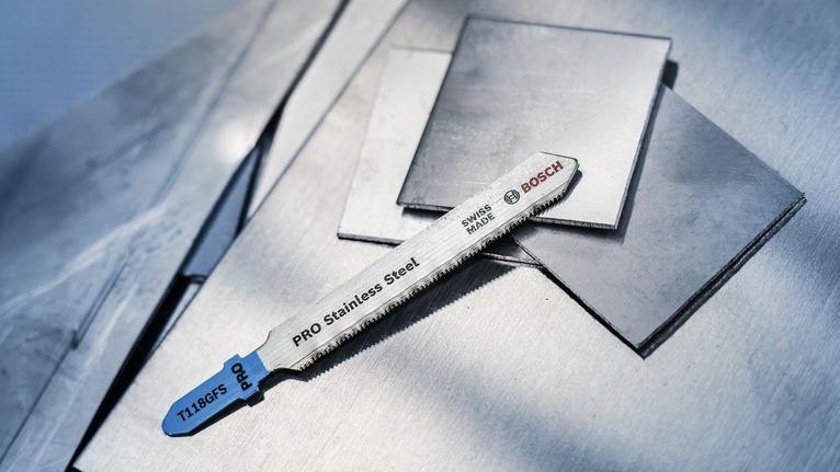 Jigsaw blade for stainless steel resting on stacked metal sheets.