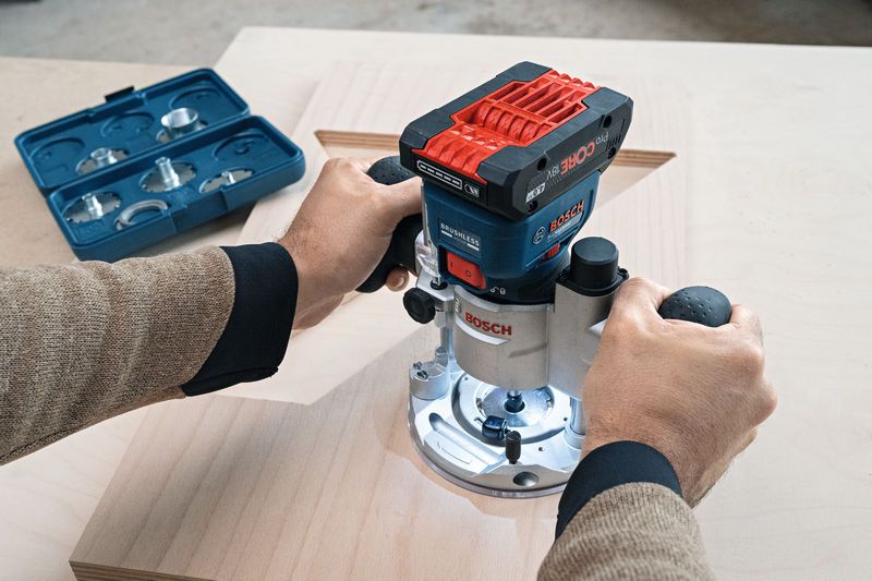GKF 18V-8 A person uses a cordless palm router to shape a wooden board.