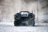 Rugged jobsite radio sitting on a dusty concrete floor in a partially finished building.
