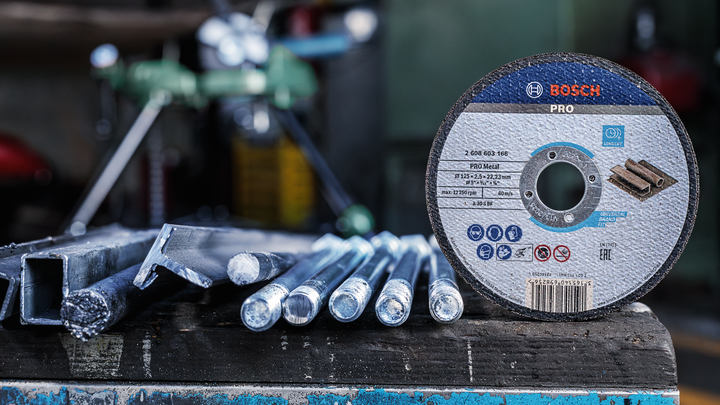 Object #200467093: 3089912_app_web_2 Cutting disc placed on a workbench beside several metal rods in a workshop.