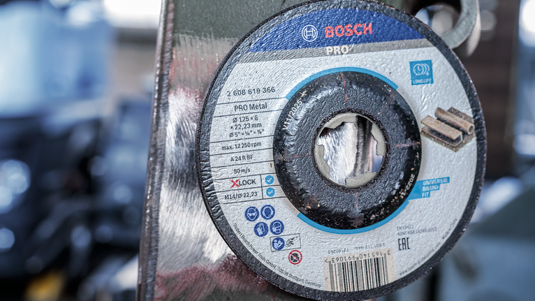 PRO Metal Bonded Grinding Disc, 125 x 6 x 22.23 mm, X-Lock Metal cutting disc mounted on a grinder in a workshop.