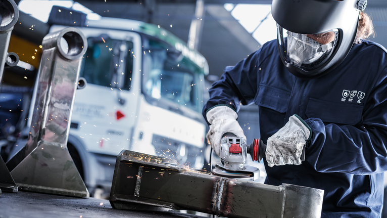 PRO Metal Bonded Grinding Disc, 125 x 6 x 22.23 mm, X-Lock Person wearing safety equipment grinds metal, creating sparks.