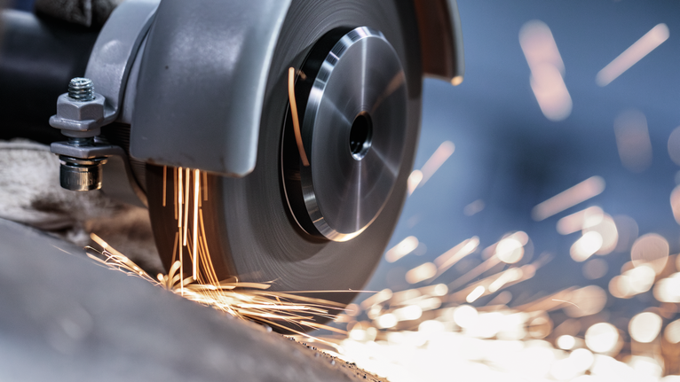 Cutting wheel spins, producing bright sparks as it grinds through metal.