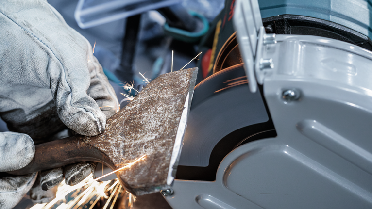 PRO Metal Grinding Wheel, 200 x 25 x 32 mm, G46 Person wearing safety equipment grinds a metal tool on a bench grinder.