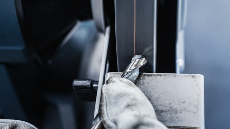 PRO Metal Grinding Wheel, 200 x 25 x 32 mm, G46 Person wearing safety equipment sharpens a drill bit on a grinding machine.