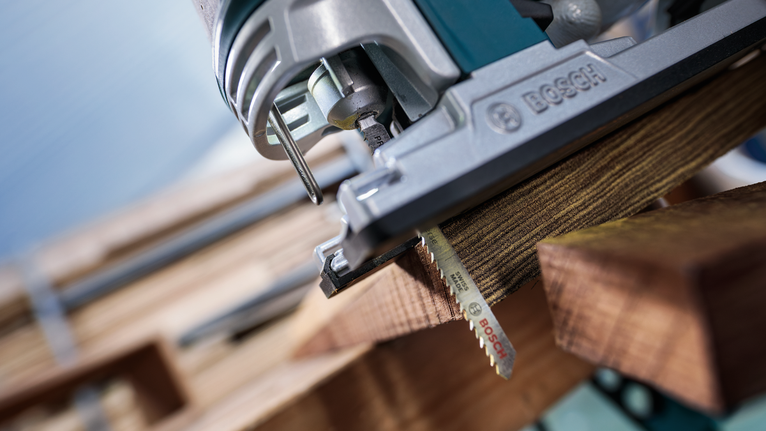 PRO Hardwood clean reverse T101BRF Jigsaw Blade, 100 mm, 5 pcs Jigsaw cutting through a piece of wood in a carpentry setting.
