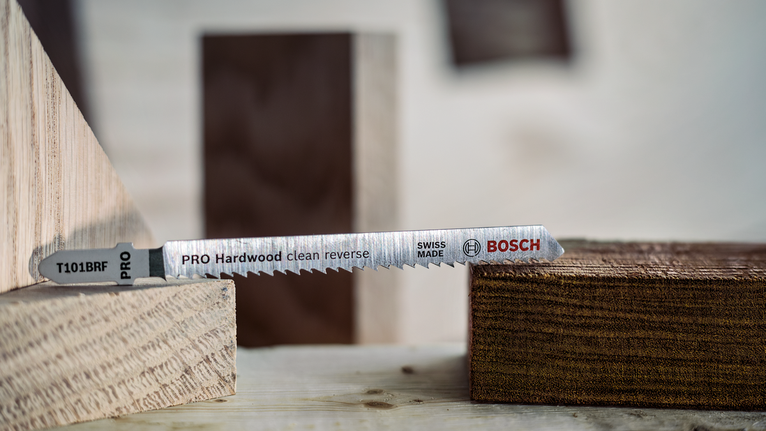 PRO Hardwood clean reverse T101BRF Jigsaw Blade, 100 mm, 5 pcs Jigsaw blade positioned between wooden blocks on a workbench.