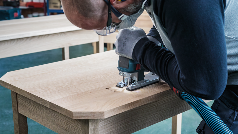PRO Hardwood clean reverse T101BRF Jigsaw Blade, 100 mm, 5 pcs Person wearing safety equipment uses a jigsaw to cut into a wooden tabletop.
