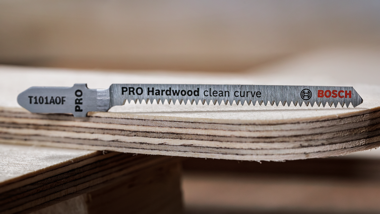 PRO Hardwood clean curve T101AOF Jigsaw Blade, 83 mm, 5 pcs Jigsaw blade resting on stacked plywood pieces.