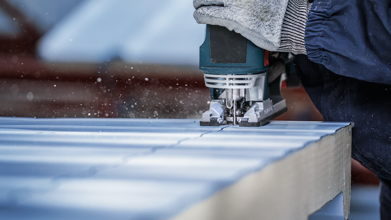 PRO Metal Sandwich T718BF Jigsaw Blade, 180 mm, 3 pcs Person wearing safety equipment uses a jigsaw to cut a straight line in a panel.