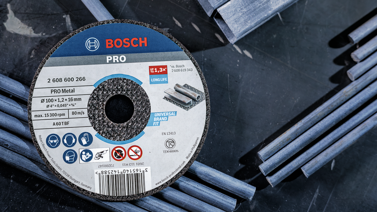 Grinding disc placed on a dark surface with scattered metal rods.